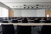 Empty seats in a lecture hall in front of a large three piece white board