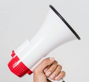 A person’s hand holding a white and red megaphone with a black strap against a plain background.
