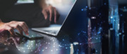 Hands use a laptop and tablet beneath an overlay of connected digital data points and flowing network graphics.