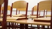 Empty classroom with wooden chairs placed in rows.