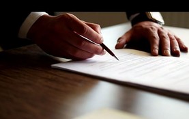 image of a man signing a piece of white paper