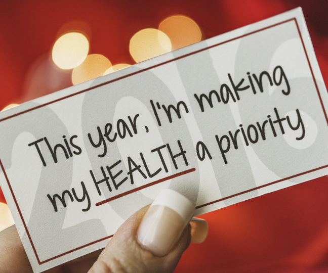 Woman holding card that reads, this year, I am making my health a priority.