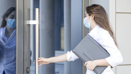 Woman wearing mask opening door