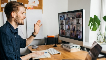 Man waving at computer screen during a video call