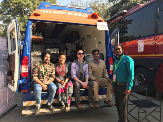 Robinson sitting on the back of a food truck with staff