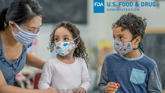 two students with their teacher wearing masks in the classroom