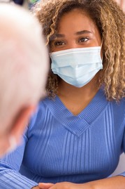 A woman wearing a mask and speaking with a health care provider