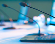 Image of a conference table with laptop computers and microphones.