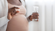 Pregnant women taking pill with glass of water