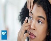 Woman placing contact lens in eye.