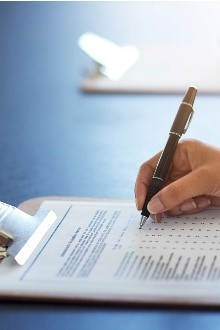A hand holding a pen completing a written survey. 