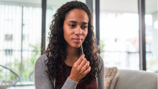 A woman performing a nose swab for a COVID-19 at home test.