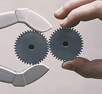 Image representing advanced manufacturing (robot hand and human hand fit gears together)