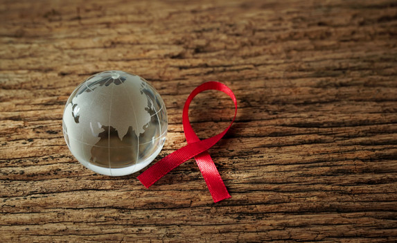 Crystal globe with red ribbon on wooden floor representing World Aids Day