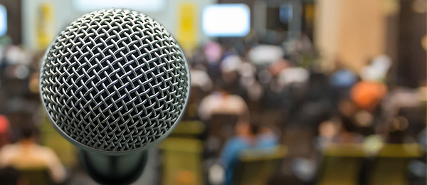 Microphone and audience, representing Public Meeting on Patient-Focused Drug Development for Long COVID
