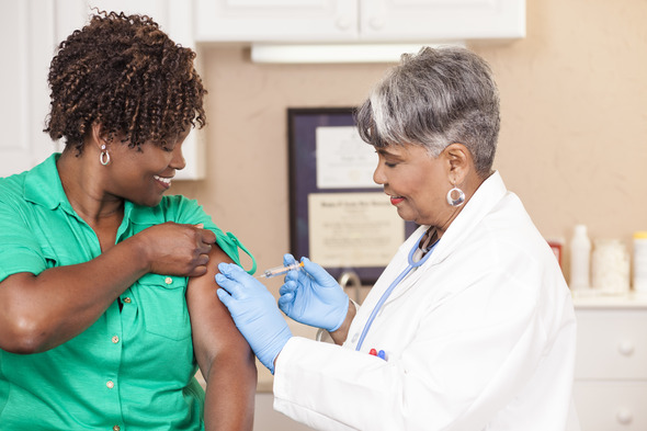 Female health care professional giving female patient flu vaccine