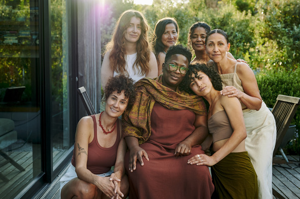 A group of diverse women sit together outside 