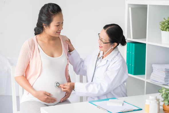 A health care provider examines a pregnant patient during an office visit 