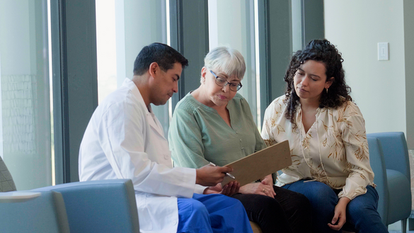 Two women looking over a clipboard with a health care provider. 