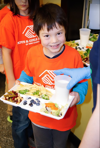 A participant of the Wallingford Boys and Girls Club smiles with his lunch! He is eating local Washington blueberries. 