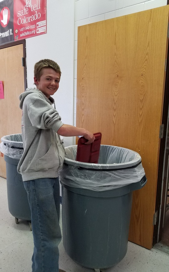 Boy dumps his lunch tray into a school cafeteria trash can