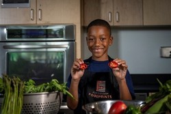 Child holds red pepper in test kitchen