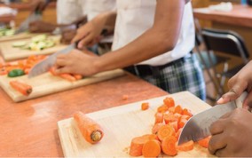 Children chopping up carrots on cutting boards