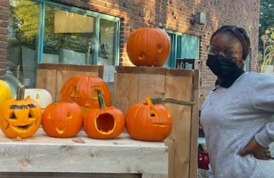 Girl standing next to table full of carved pumpkins