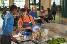 student getting lunch from the cafeteria tray line