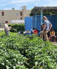 Urban farmer, teacher, and kids in an outdoor urban farm 