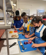 Four elementary school kids and a chef preparing a healthy meal 