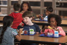 Children eating strawberries and bananas at a lunch table. 
