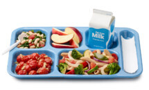 School meal tray with apples, bean salad, vegetables, and milk