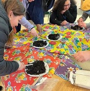 People planting seeds in dirt on paper plates 