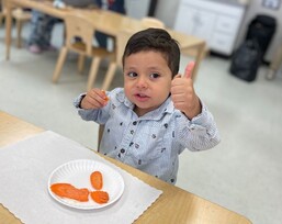 Young boy gives a thumbs up while eating sliced carrots. Courtesy Photo