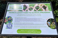 White and green sign about farm to school in outdoor garden 