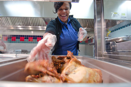 Woman serving chicken in cafeteria 