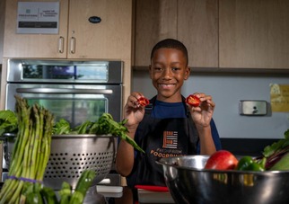 child in the kitchen with fresh fruits and vegetables