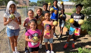 Children holding squash in a garden.