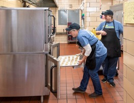 Food service worker putting food into an oven. 