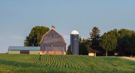 A photo of a barn and silo. 