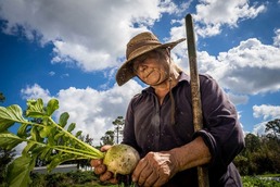 Woman holding a radish in a field. 