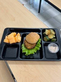 Fishcake Sandwich on a tray with squash and mellon