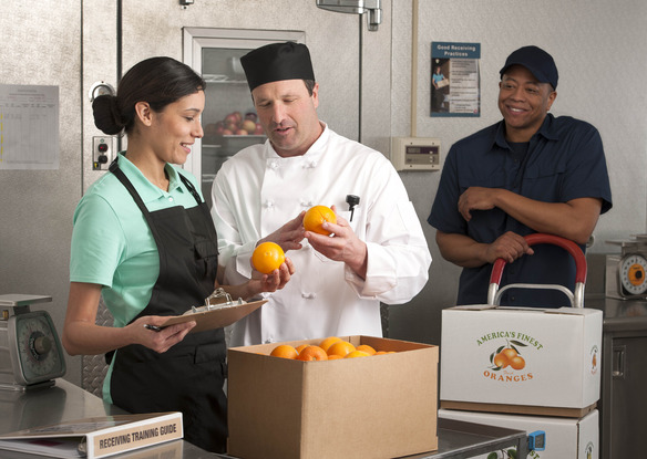 School lunch staff inspecting orange quality