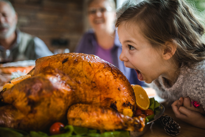 Girl about to take a bite from a cooked turkey