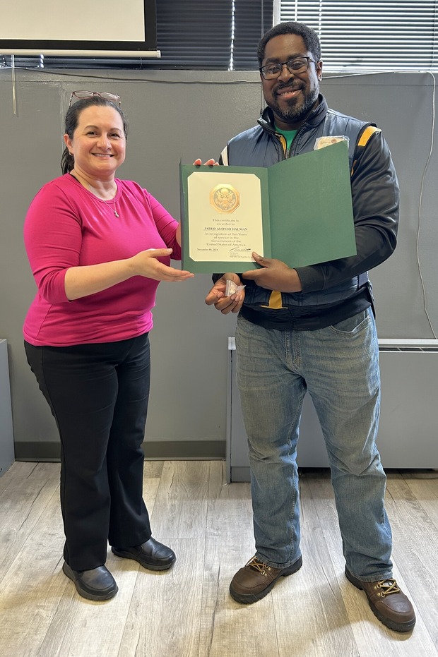 CSI Jared Halman holding his new ten-year service certificate and pin