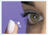 Woman placing contact lense on eye