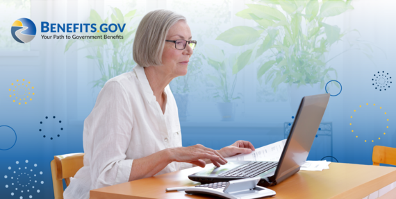 Mature woman in a bright kitchen prepares her federal tax returns using a laptop