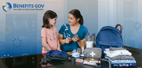 A young girl and her mother pack an emergency supply kit with water bottles, spare clothing, and other necessities