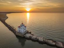 Lighthouse situated on a small island in the middle of very calm water.